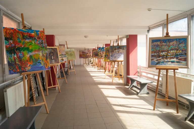 Colorful paintings displayed in a sunlit art academy corridor in Kyiv, Ukraine.